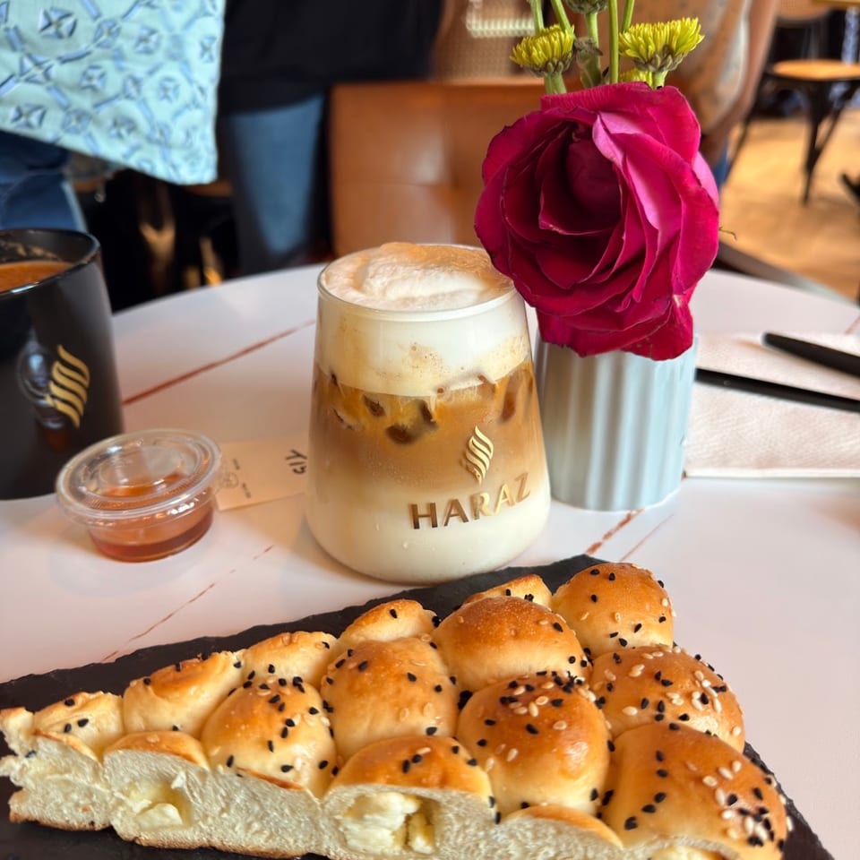 Haraz iced coffee and bread beside a rose.